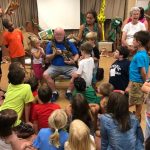 Photo of many children gathered around their teacher